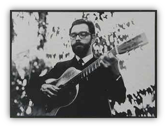 Black and white photo of a man playing guitar outdoors, wearing glasses and a suit.