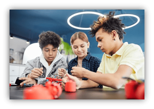 Three children engaged in hands-on robotics activity, focused on building with red components.