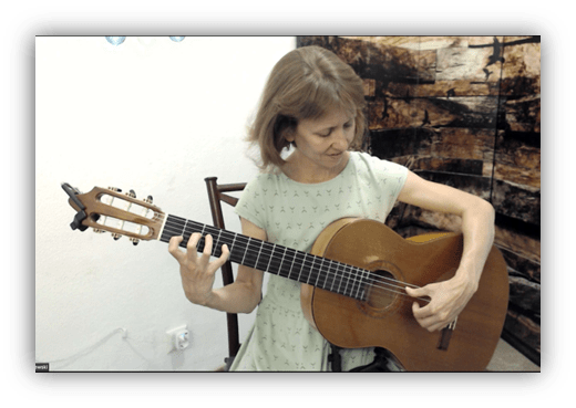 Woman playing classical guitar in a cozy indoor setting.