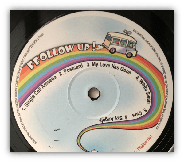 "Vinyl record label with song titles and colorful rainbow design."