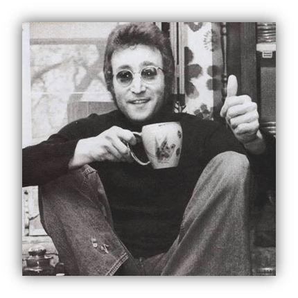 "Black and white photo of a smiling man with glasses, holding a coffee mug and giving a thumbs up."
