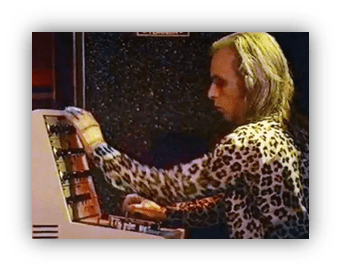 Musician playing synthesizer in leopard print shirt.