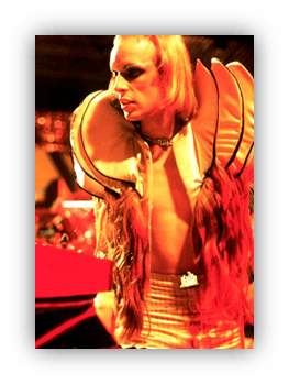 "Performance artist in dramatic costume with bold makeup and bright lighting."