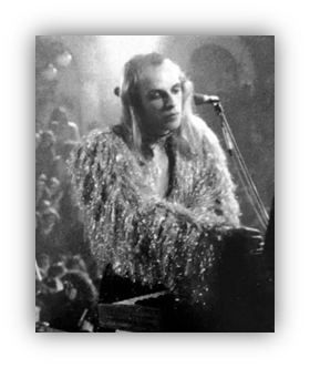 Musician performing on stage in a glittery outfit, black and white image.