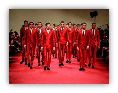 "Fashion show featuring male models in red suits walking a runway."